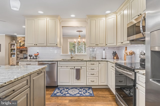 kitchen with ornamental molding, stainless steel appliances, sink, pendant lighting, and dark hardwood / wood-style floors