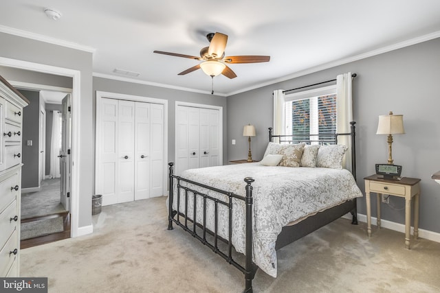 bedroom with multiple closets, crown molding, ceiling fan, and light carpet