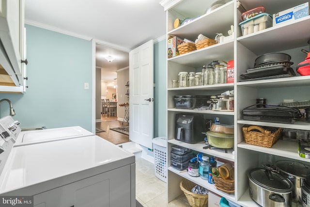 laundry area with cabinets, light tile patterned floors, crown molding, and washing machine and clothes dryer