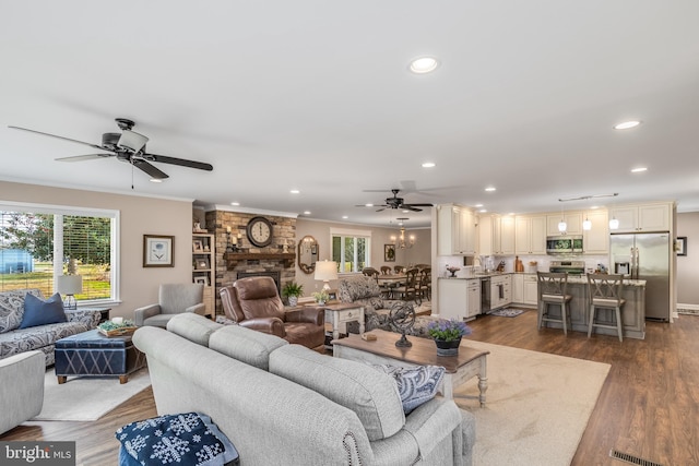 living room with ceiling fan, ornamental molding, dark wood-type flooring, and a brick fireplace