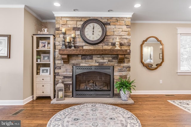 interior space with wood-type flooring, a stone fireplace, and ornamental molding