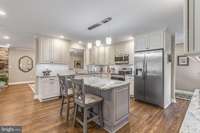 kitchen featuring a kitchen breakfast bar, light stone counters, stainless steel appliances, dark wood-type flooring, and hanging light fixtures