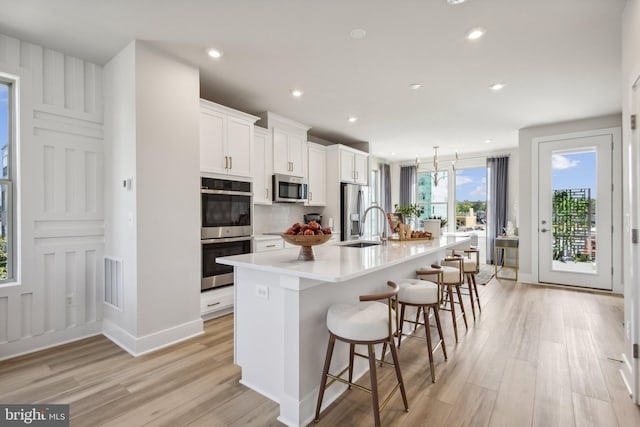 kitchen featuring appliances with stainless steel finishes, white cabinetry, a spacious island, and a breakfast bar area