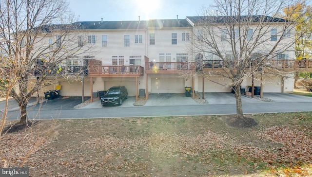 back of property with a garage, a deck, and central AC