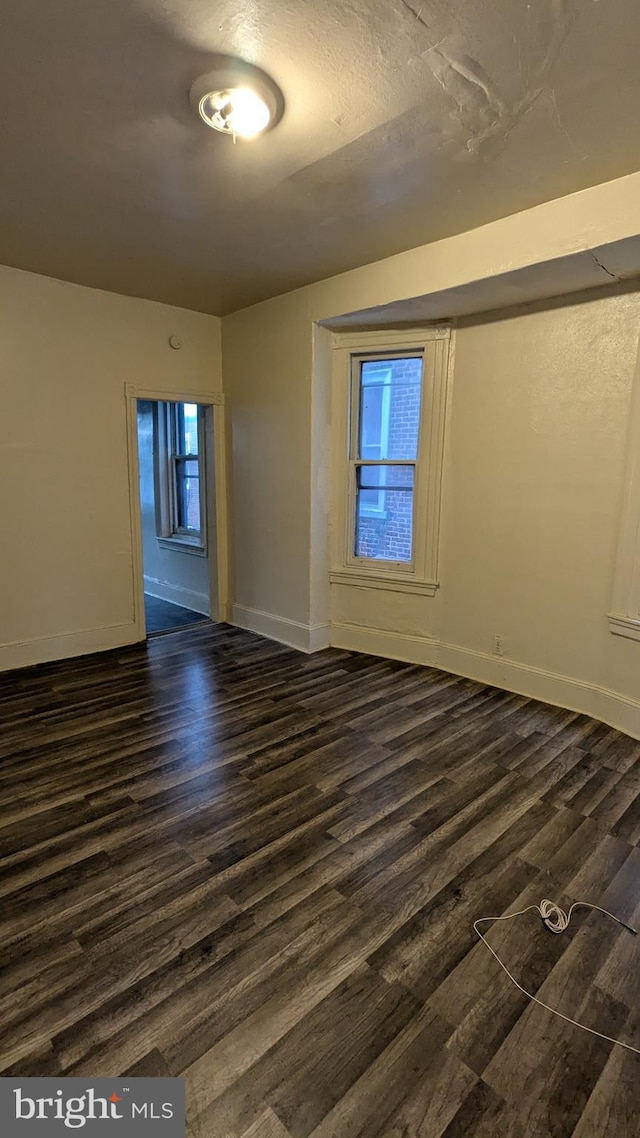 unfurnished room with a textured ceiling and dark wood-type flooring