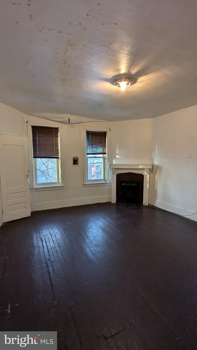 unfurnished living room with dark hardwood / wood-style floors and a healthy amount of sunlight