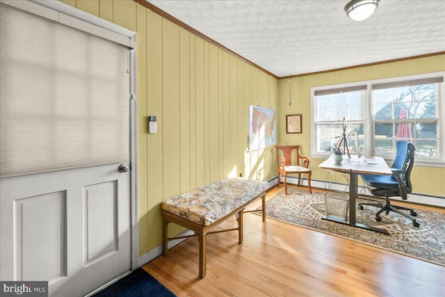 office space with a textured ceiling, light hardwood / wood-style flooring, crown molding, and wood walls