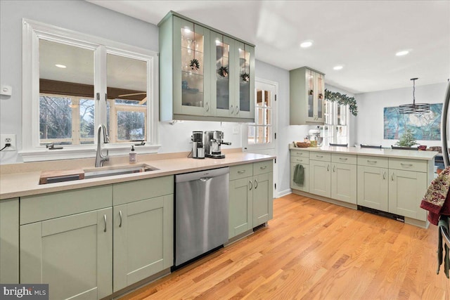 kitchen featuring sink, hanging light fixtures, stainless steel dishwasher, light wood-type flooring, and green cabinetry