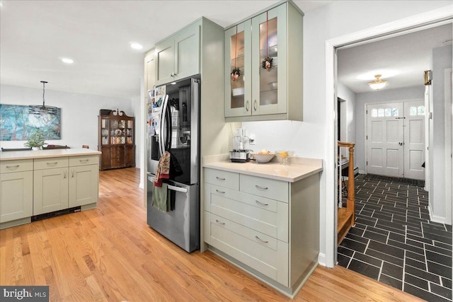 kitchen with stainless steel fridge, light wood-type flooring, hanging light fixtures, and green cabinets