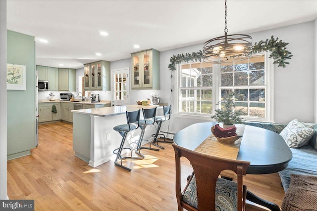 dining area featuring light hardwood / wood-style floors, baseboard heating, and a notable chandelier