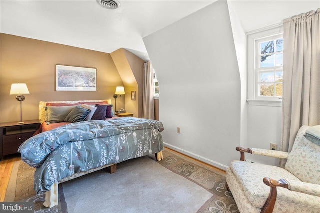 bedroom with vaulted ceiling and hardwood / wood-style flooring