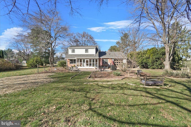 rear view of house featuring a lawn, a sunroom, and a patio