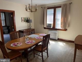 dining room featuring carpet floors, radiator heating unit, cooling unit, and an inviting chandelier