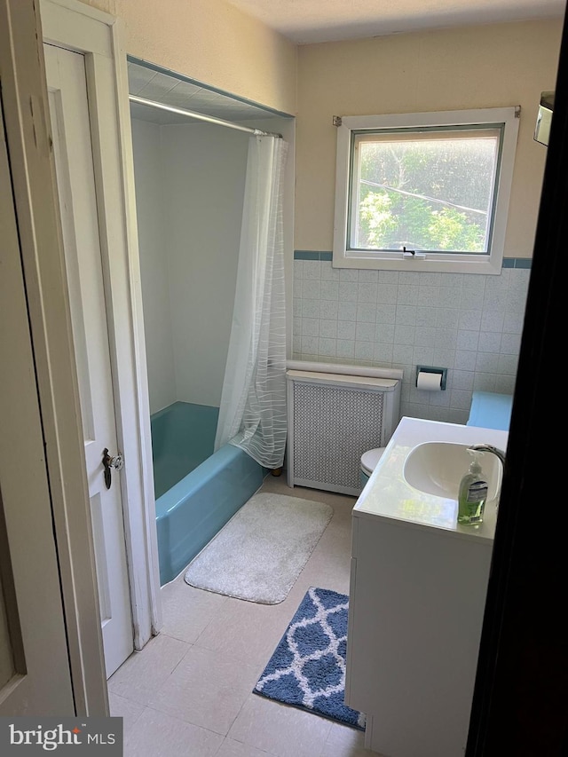 full bathroom with radiator heating unit, tile walls, toilet, vanity, and shower / tub combo