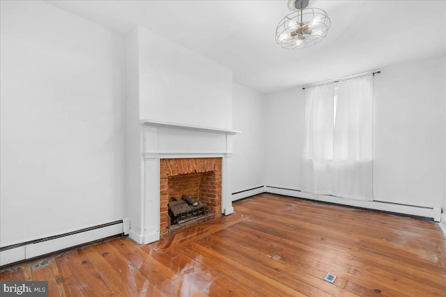 unfurnished living room featuring a brick fireplace, wood-type flooring, and a baseboard heating unit