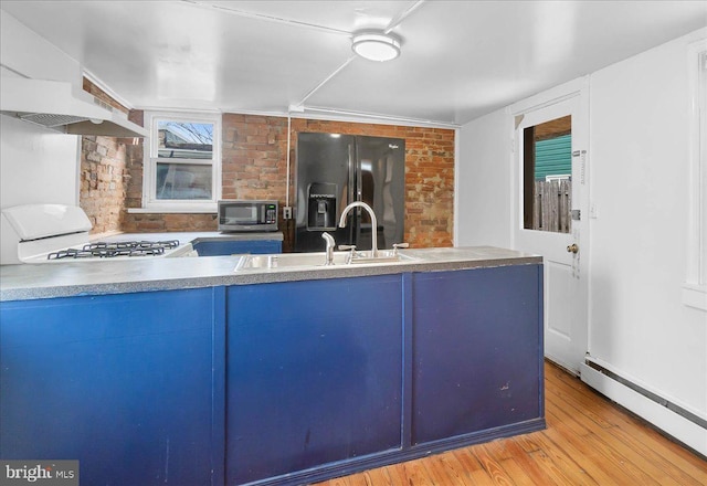 kitchen featuring black refrigerator with ice dispenser, a baseboard heating unit, sink, light wood-type flooring, and white range oven