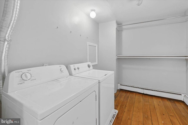 clothes washing area featuring washing machine and clothes dryer, hardwood / wood-style floors, and a baseboard heating unit