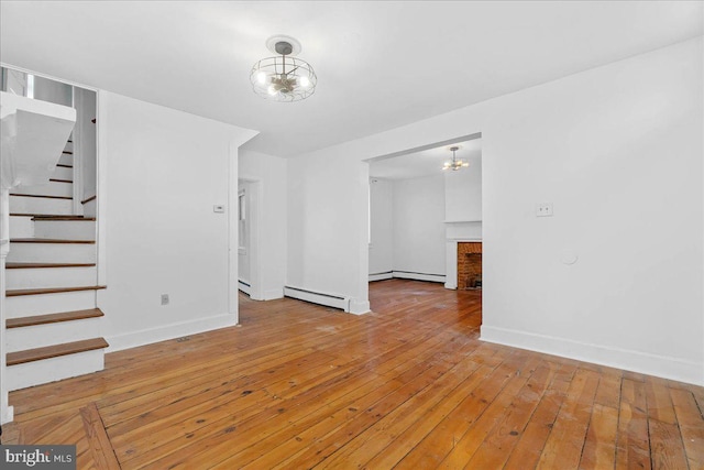 unfurnished living room featuring an inviting chandelier, light hardwood / wood-style floors, a baseboard radiator, and a brick fireplace