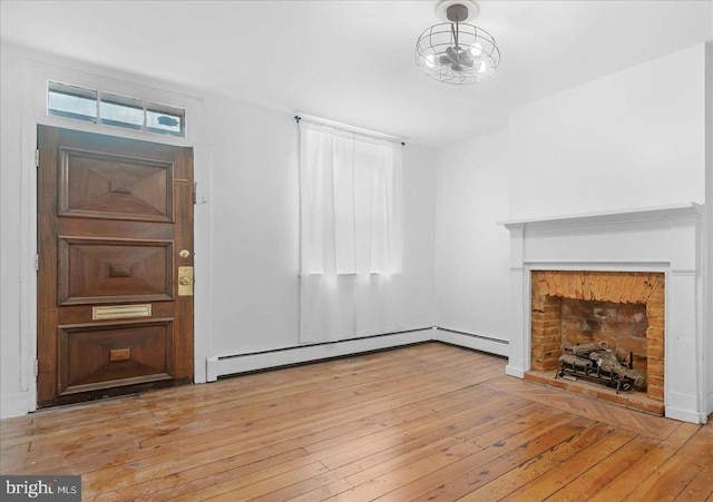 unfurnished living room featuring baseboard heating and light hardwood / wood-style flooring