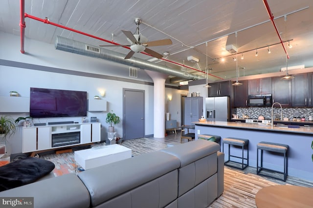 living room with ceiling fan, sink, and light wood-type flooring