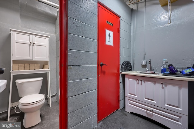 bathroom with vanity, concrete flooring, and toilet