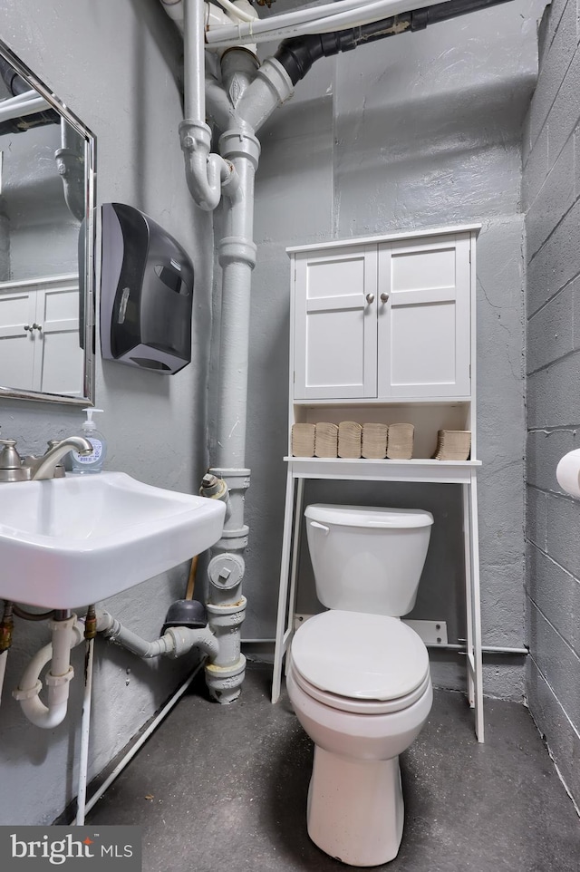 bathroom featuring toilet, concrete flooring, and sink