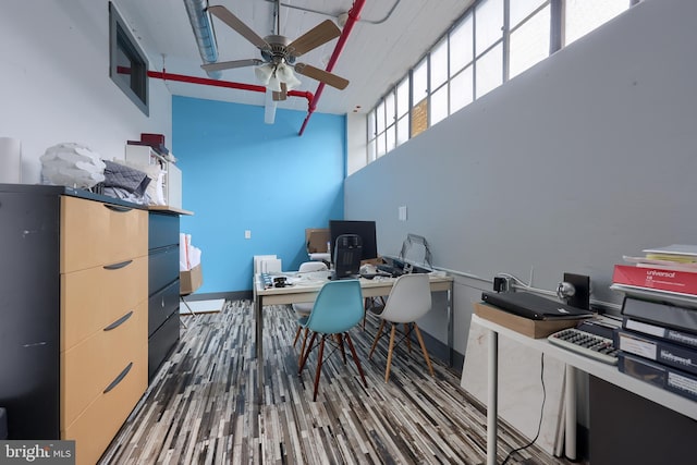 home office featuring ceiling fan, a towering ceiling, and dark hardwood / wood-style floors