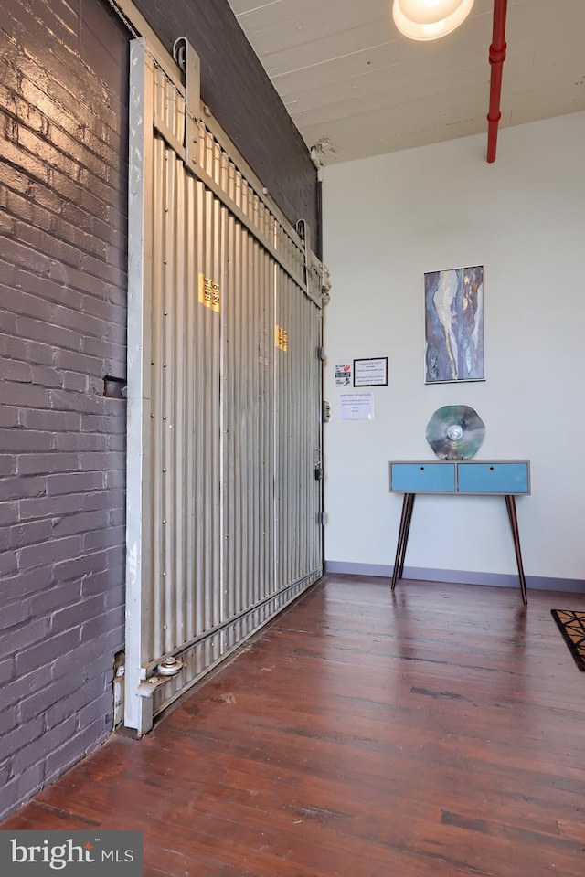 hallway with dark hardwood / wood-style flooring and brick wall