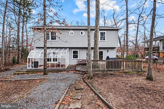 rear view of house featuring a sunroom and a deck