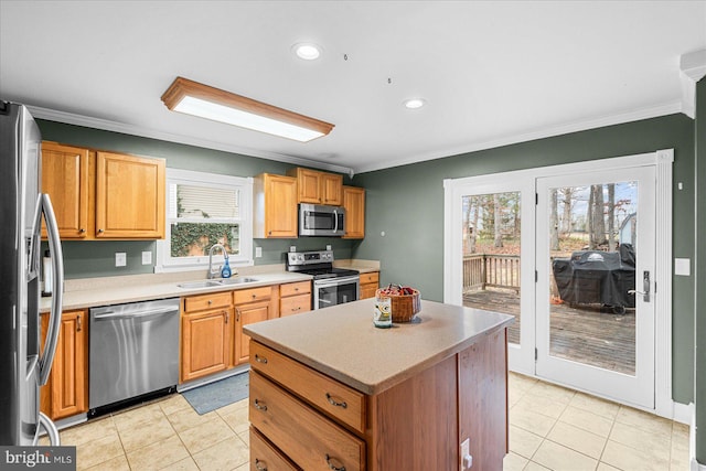 kitchen with sink, light tile patterned floors, ornamental molding, appliances with stainless steel finishes, and a kitchen island