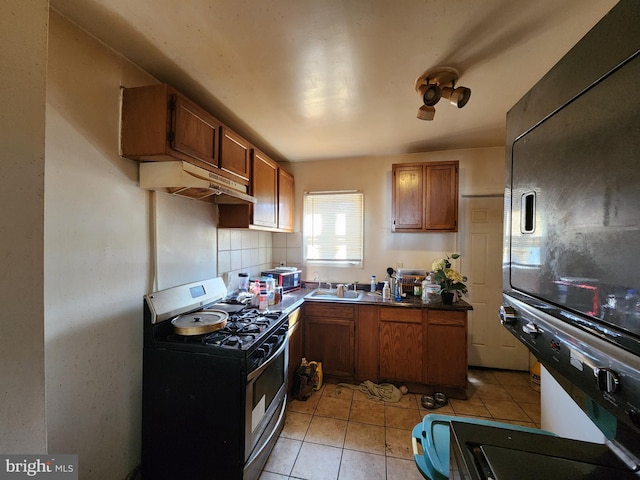 kitchen with sink, black fridge, range with gas cooktop, decorative backsplash, and light tile patterned flooring