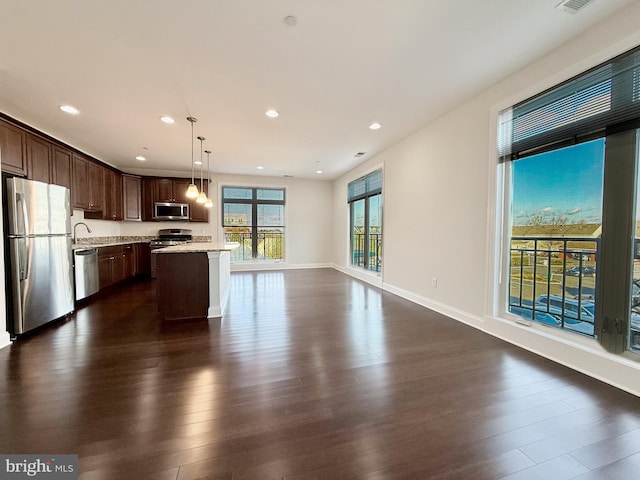 kitchen with a center island, dark hardwood / wood-style floors, decorative light fixtures, and appliances with stainless steel finishes