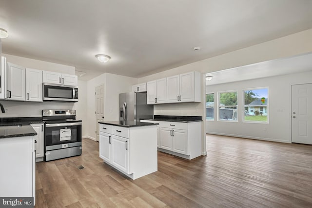 kitchen with light wood-type flooring, stainless steel appliances, white cabinetry, and sink