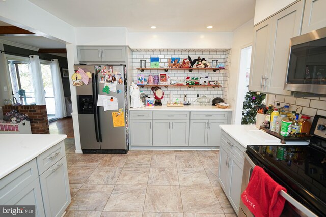 kitchen with gray cabinetry, decorative backsplash, ornamental molding, and appliances with stainless steel finishes