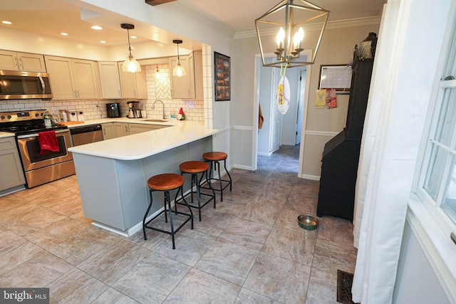 kitchen with kitchen peninsula, ornamental molding, a breakfast bar, stainless steel appliances, and pendant lighting