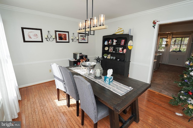 dining space featuring crown molding, a notable chandelier, and hardwood / wood-style flooring