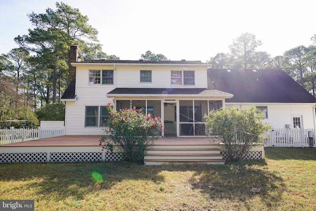 rear view of house with a lawn, a wooden deck, and a sunroom