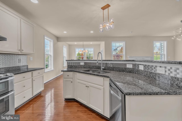 kitchen with a chandelier, stainless steel appliances, white cabinetry, and sink