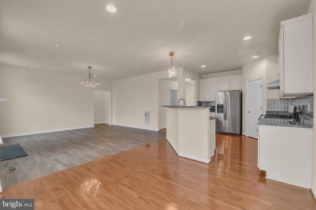 kitchen featuring hanging light fixtures, light hardwood / wood-style flooring, appliances with stainless steel finishes, tasteful backsplash, and white cabinetry