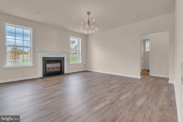 unfurnished living room with light hardwood / wood-style flooring and a chandelier