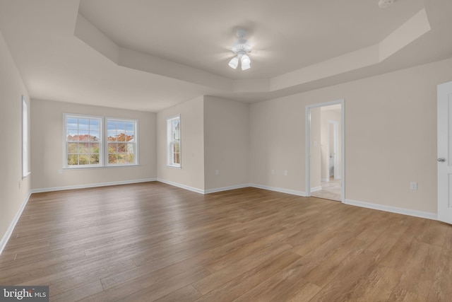 spare room featuring ceiling fan, light hardwood / wood-style floors, and a raised ceiling