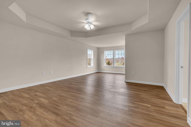 empty room featuring hardwood / wood-style floors, a tray ceiling, and ceiling fan