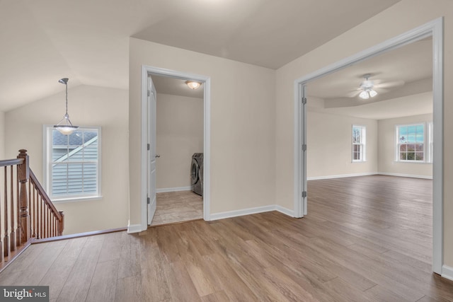 empty room featuring ceiling fan, light hardwood / wood-style floors, lofted ceiling, and washer / dryer