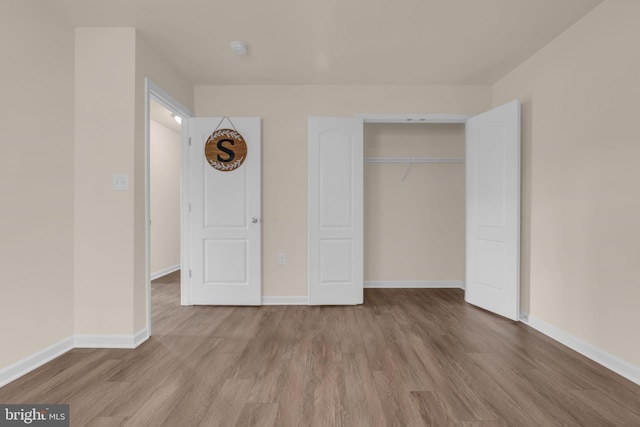 unfurnished bedroom with light wood-type flooring and a closet