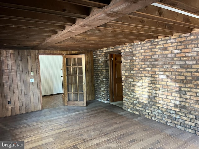 spare room with wood walls, wood-type flooring, and brick wall