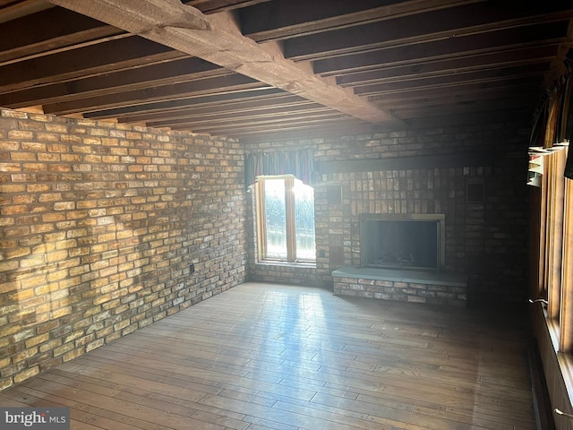 unfurnished living room featuring hardwood / wood-style floors, a fireplace, and brick wall