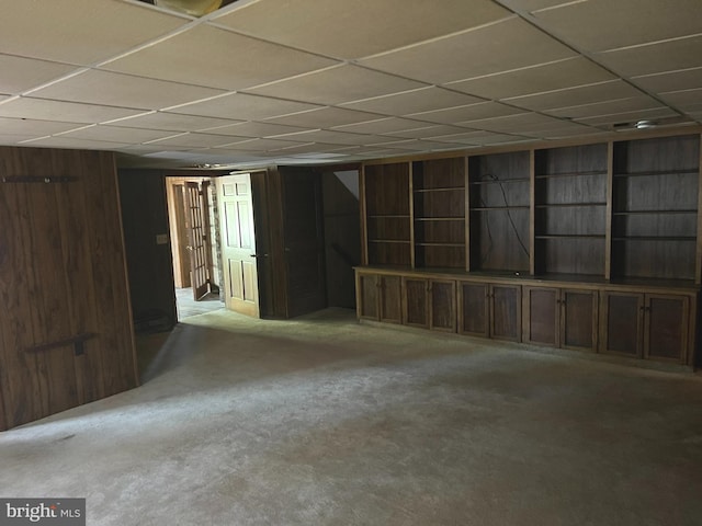 basement with wood walls and a drop ceiling