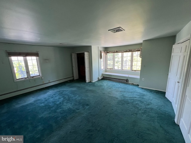 unfurnished living room featuring dark carpet, a wealth of natural light, and a baseboard heating unit