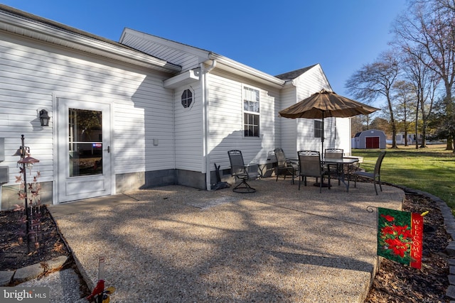 rear view of house with a storage unit, a yard, and a patio