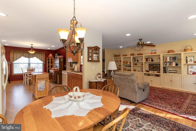 dining area featuring ceiling fan with notable chandelier and light wood-type flooring